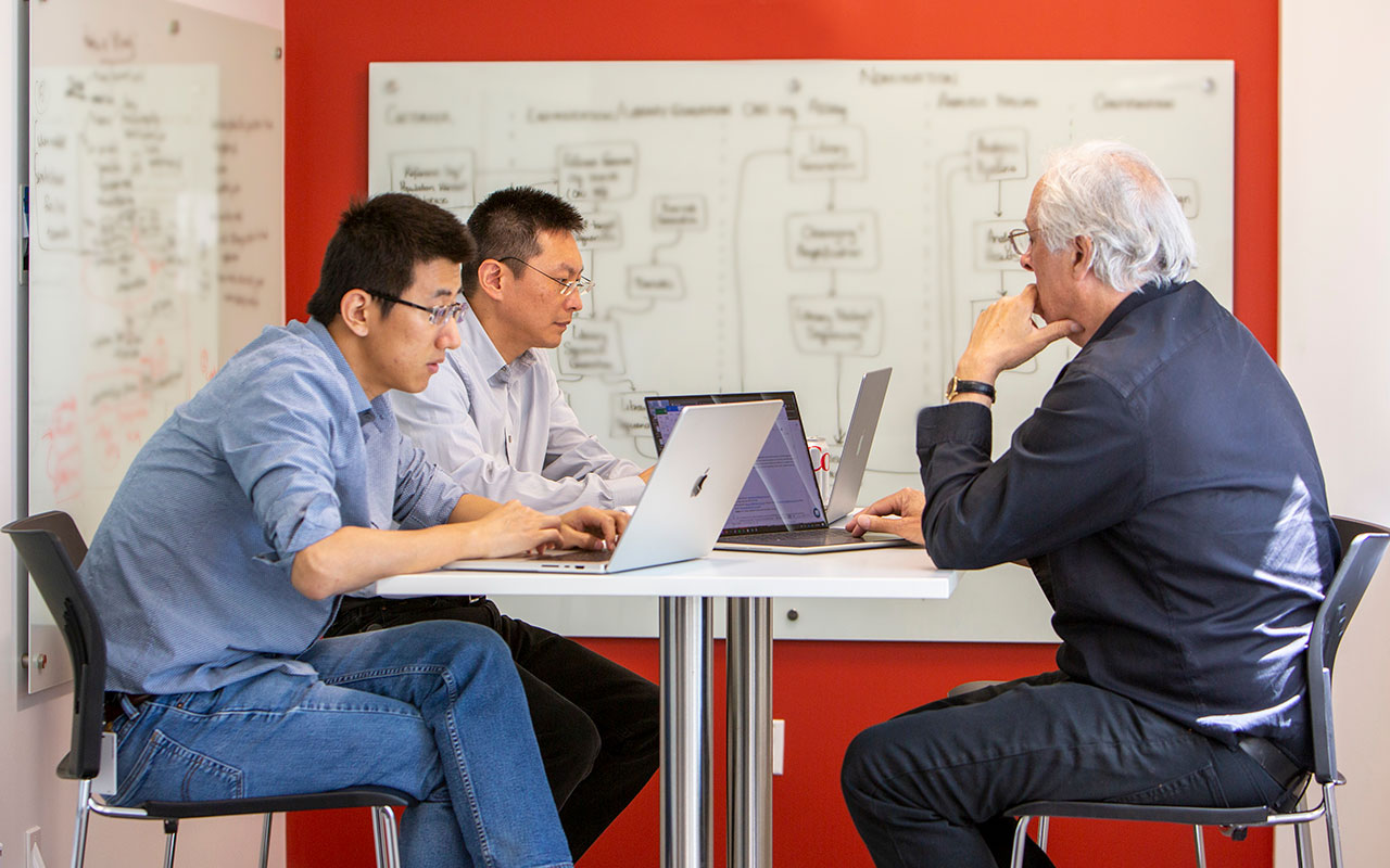 SeQure team meeting with laptops and whiteboard